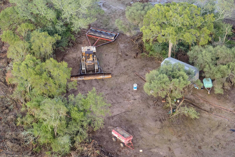 Vista aérea de una zona desmontada en el Gran Chaco, donde se observa maquinaria pesada rodeada por vegetación nativa parcialmente arrasada y algunos elementos de infraestructura rural.