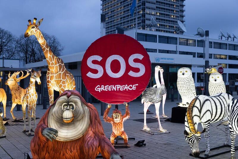 Instalación de Greenpeace con figuras de animales y un cartel rojo de SOS frente a la sede de la ONU.